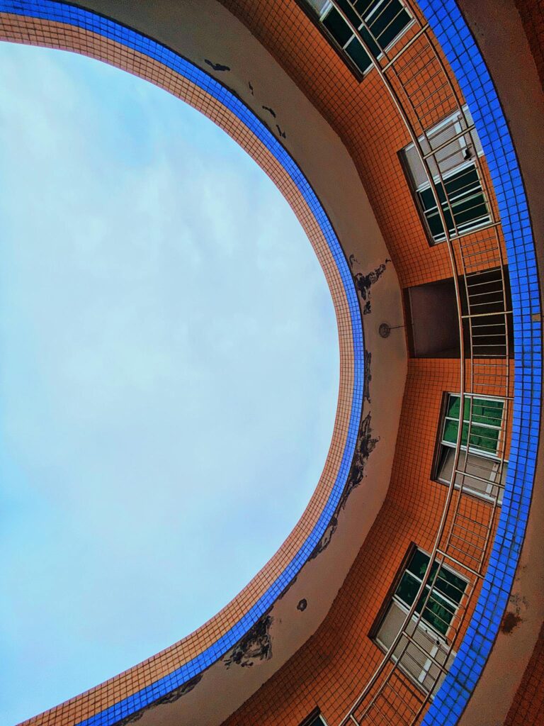 Low angle view of a circular residential building with a visible blue sky through the opening.